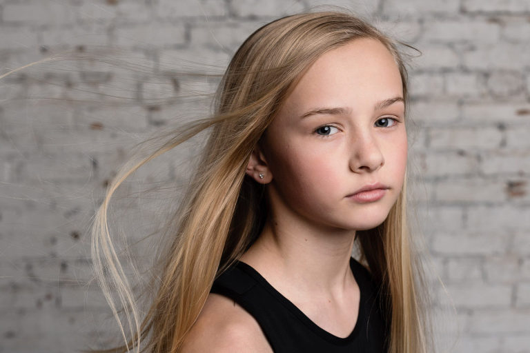 Tip for your photo shoot: Know your why. A preteen girl looks directly into the camera during her photo shoot at a local gym.