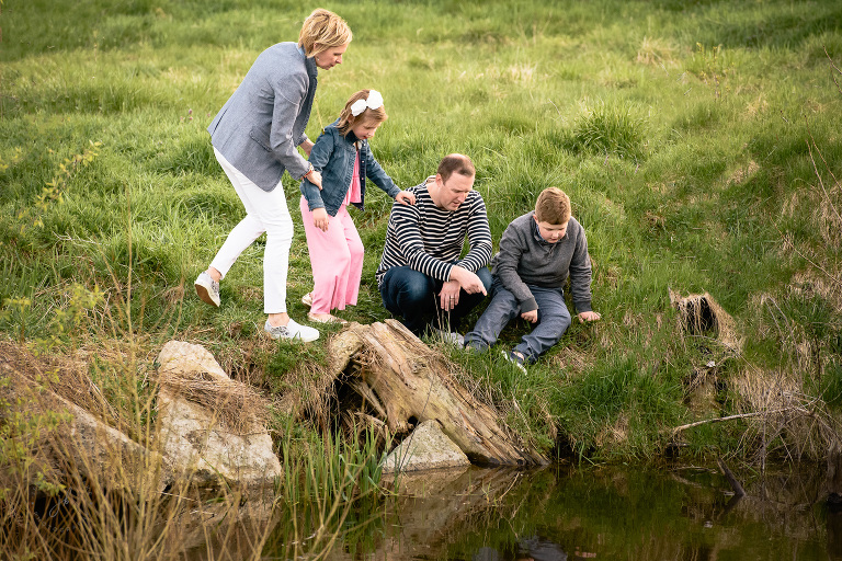 family observing fish in a pond