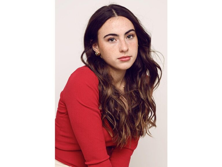 Magazine style photograph of a pretty, freckled teen girl who engages with the viewer.